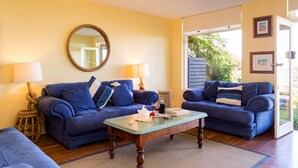 A living room with two blue sofas, a wooden coffee table, and a round mirror on the wall. - Oceanfront Haven with Unparalleled Views and Retreat Living (Victor Harbor)
