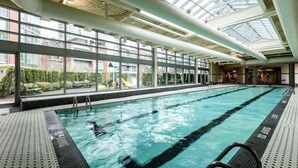 Une piscine intérieure avec des parois en verre transparent, une verrière et une vue sur l’extérieur.