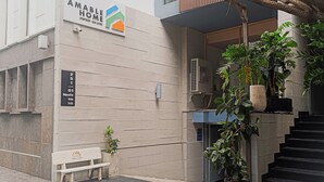 A building with a sign reading "AMABLE HOME APARTMENT - REAL ESTATE" and a bench with a sign "THE GUARD". - Tranquil Studio with Kitchen near Airport in bustling area (Ho Chi Minh City)