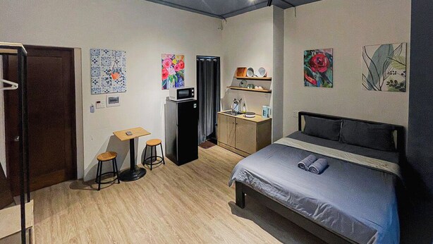 A compact room with a bed, a small table, a stool, a microwave, and a cabinet. - Tranquil Studio with Kitchen near Airport in bustling area (Ho Chi Minh City)