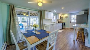 A kitchen with white cabinets, a wooden dining table, and a ceiling fan. - Walk to family friendly beach in West Dennis! (Dennis)