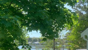 A residential area with a lawn, a white picket fence, and a parked SUV. - Walk to family friendly beach in West Dennis! (Dennis)