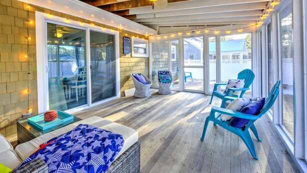 A covered patio area with a ceiling fan, wicker chairs, and a table with a blue patterned tablecloth. - Walk to family friendly beach in West Dennis! (Dennis)