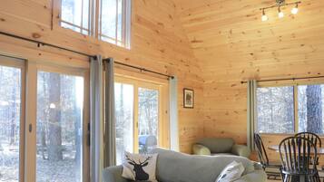 A wooden cabin interior with a sofa, a table, and a ceiling fan.