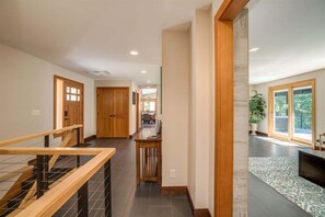 Ein modernes Interieur mit Treppe, Holztüren, einem Essbereich und Blick ins Freie.