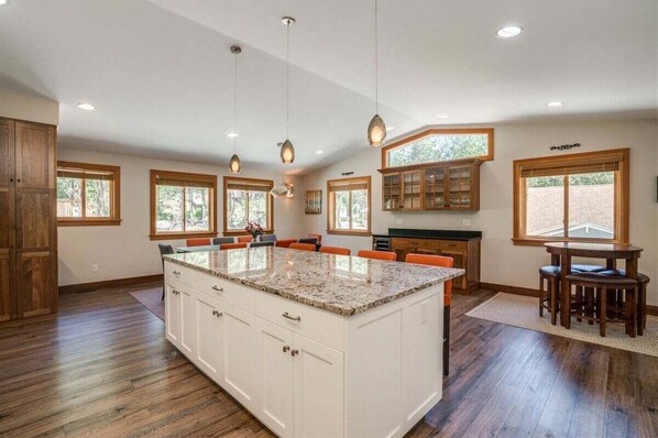 A spacious kitchen with a large island, wooden cabinets, and multiple windows.