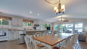A spacious kitchen with white cabinetry, a wooden dining table, and a chandelier.