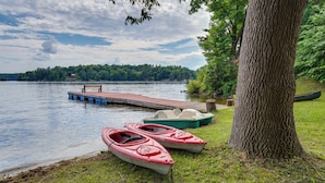A lakeside dock with a bench and two kayaks.