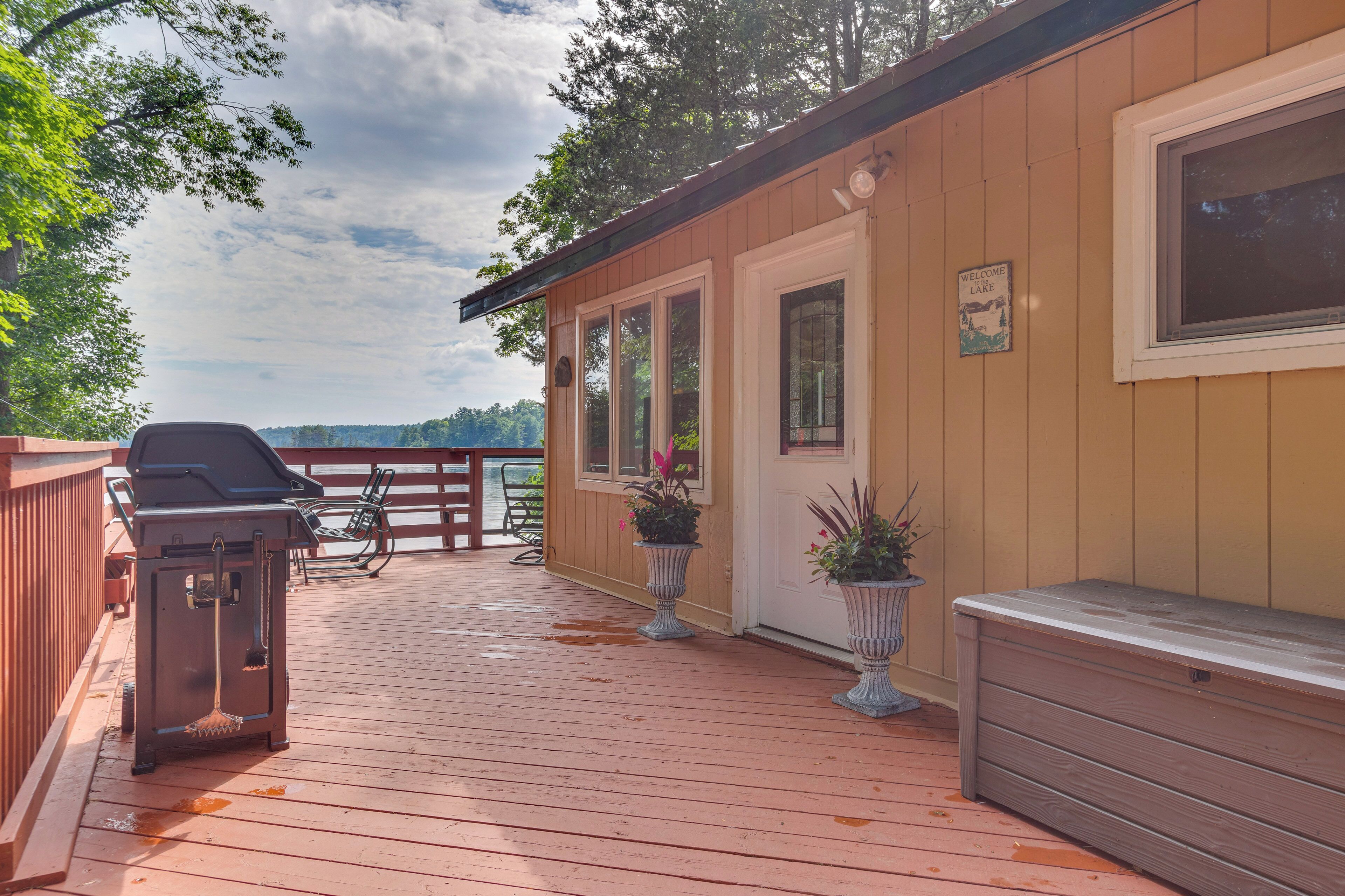 Une terrasse en bois avec un barbecue, des plantes en pot et un banc.