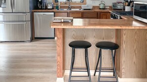 Una cocina moderna con armarios de madera, electrodomésticos de acero inoxidable, una isla grande con taburetes y un ventilador de techo.