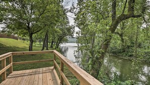 Een houten terras met uitzicht op een rustige rivier, omringd door bomen.