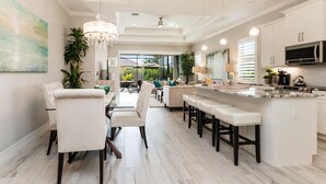 Una cocina moderna con una isla central, taburetes de bar y un comedor con sillas y mesa.