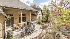 A house with a patio area featuring outdoor furniture, a hot tub, and a stone retaining wall. - BOULDER RIDGE - 7 BD, HUGE THEATER, POOL TABLE, HOT TUB, SAUNA (Sundance)