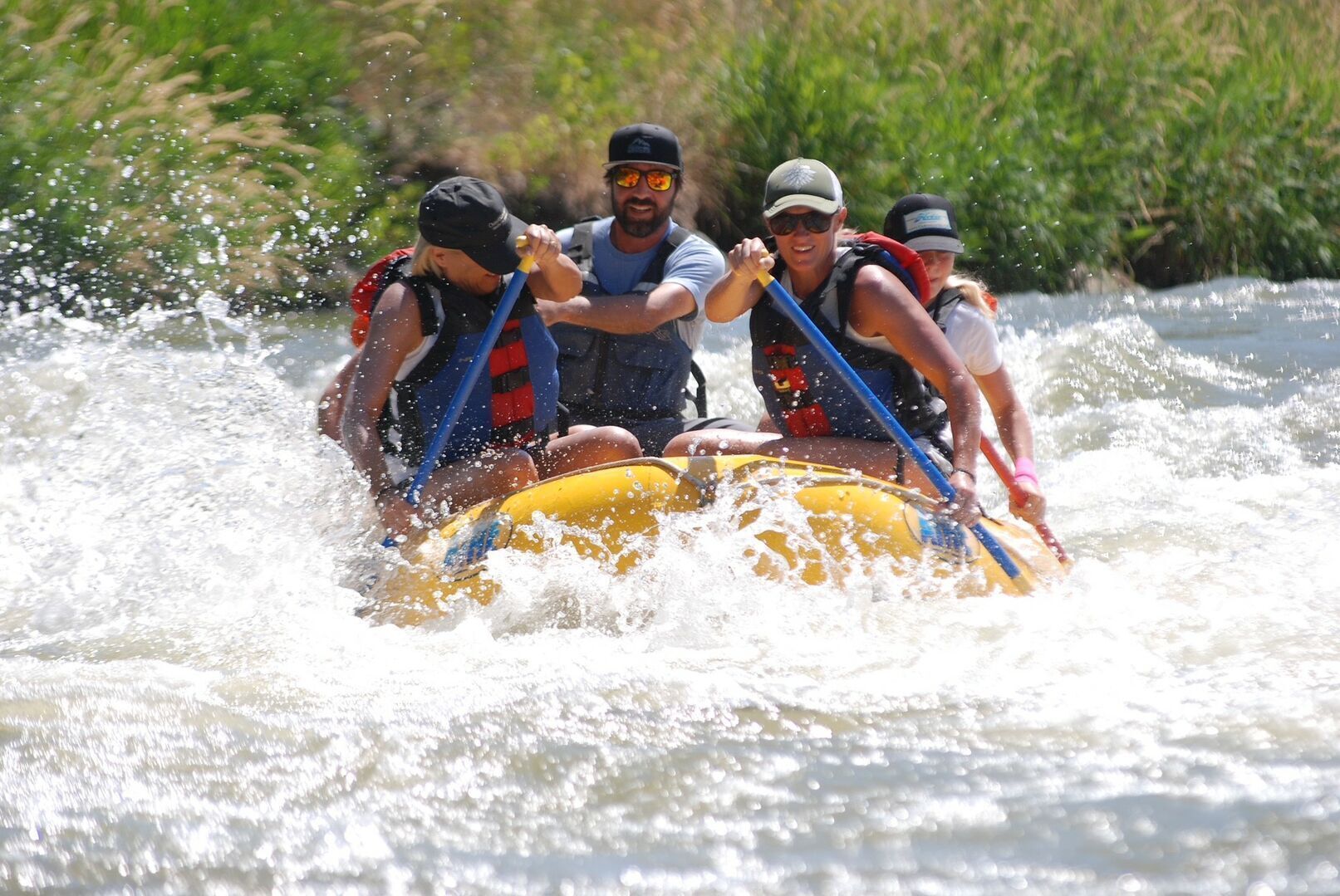 A group of people in a yellow raft navigating through a river with white water.