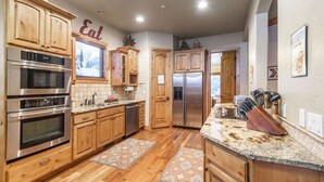 A kitchen with wooden cabinets, stainless steel appliances, a granite countertop, and a backsplash. - BOULDER RIDGE - 7 BD, HUGE THEATER, POOL TABLE, HOT TUB, SAUNA (Sundance)