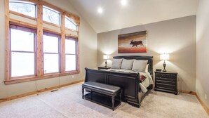 A bedroom with a large window, a bed, a bench, and a nightstand with a lamp. - BOULDER RIDGE - 7 BD, HUGE THEATER, POOL TABLE, HOT TUB, SAUNA (Sundance)
