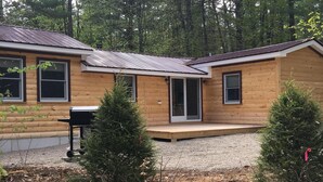 A log cabin with a gravel driveway and a small deck.