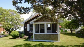 Un petit bâtiment d’un seul étage, doté d’un toit en pente, d’un porche à l’avant et d’une fenêtre.