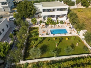 Ein modernes, zweistöckiges Gebäude mit Schwimmbad, Außenbereich und einem gepflegten Garten.