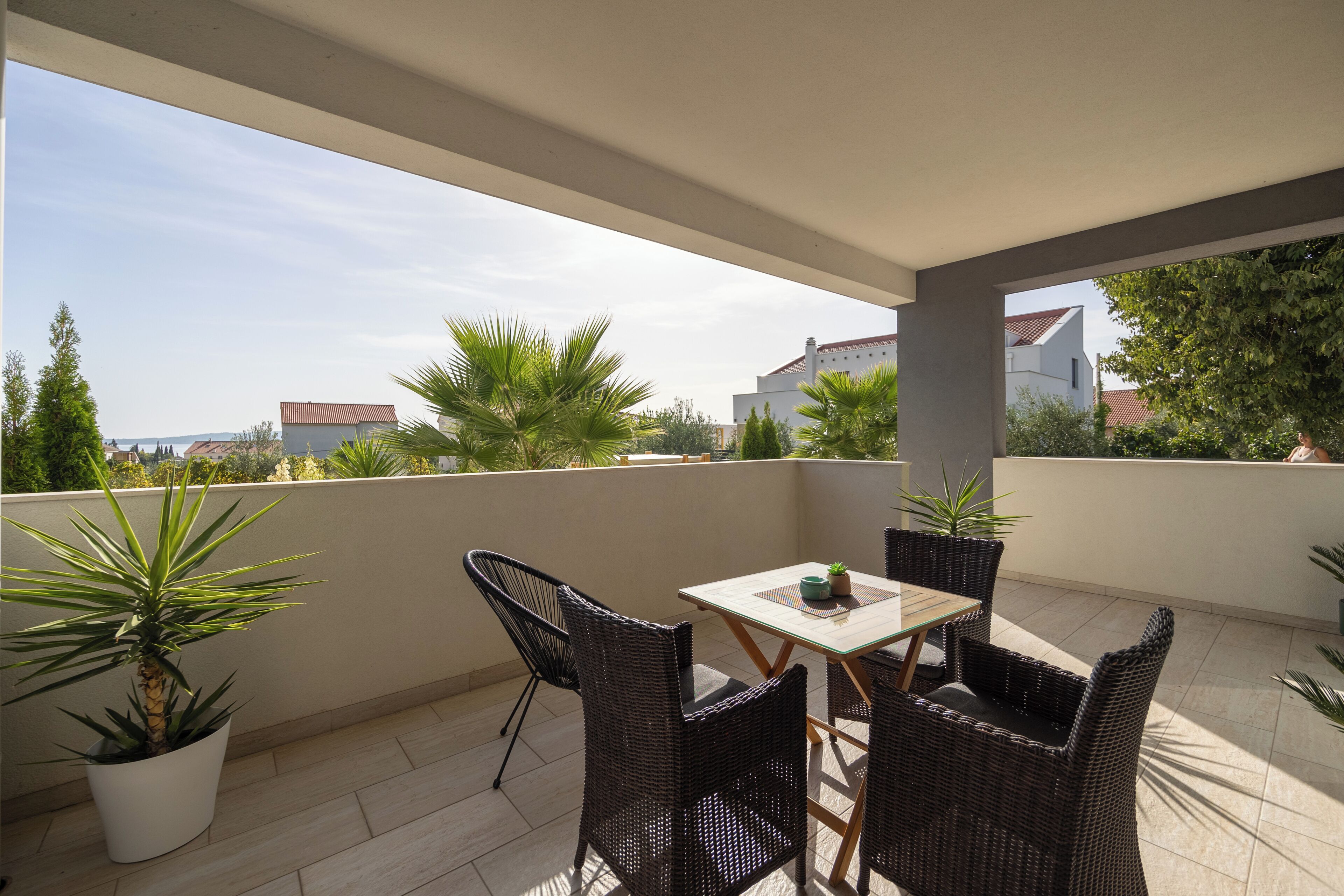 Ein Balkon mit Tisch und Stühlen, Blumentöpfen und Blick auf die Umgebung.