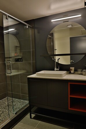 A modern bathroom with a glass shower enclosure, a round mirror, and a white sink. - Lora (Stillwater)