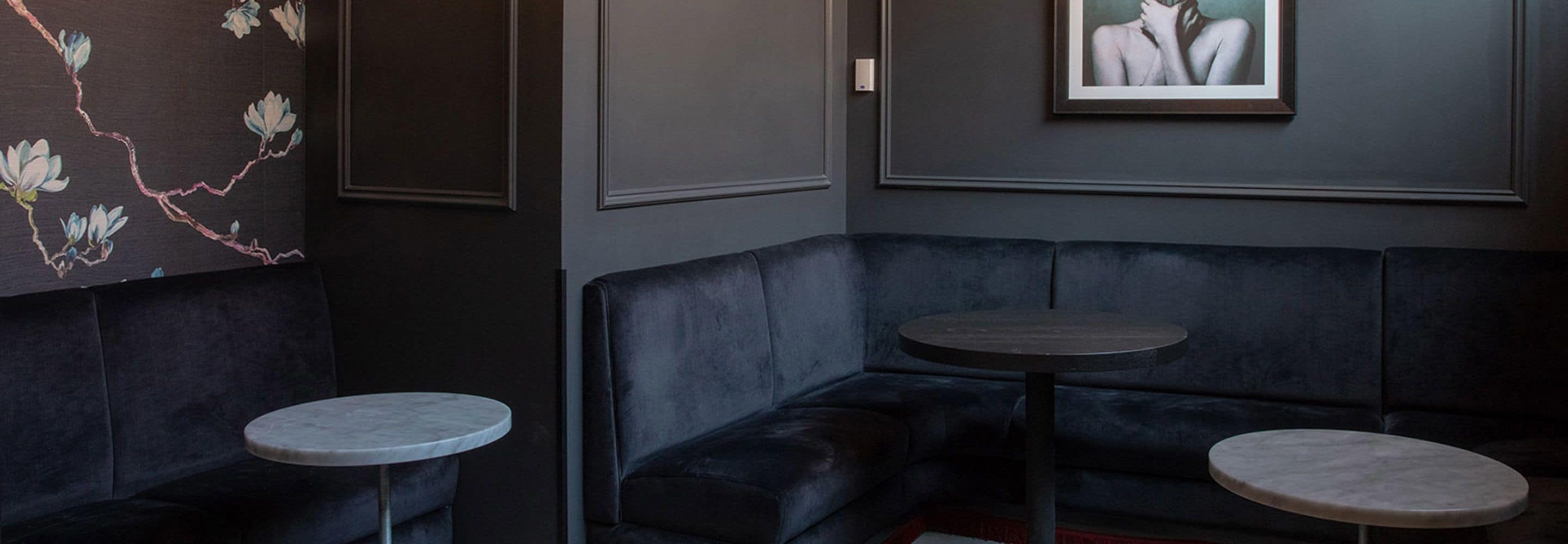 A corner seating area with a dark blue sofa and two round tables.