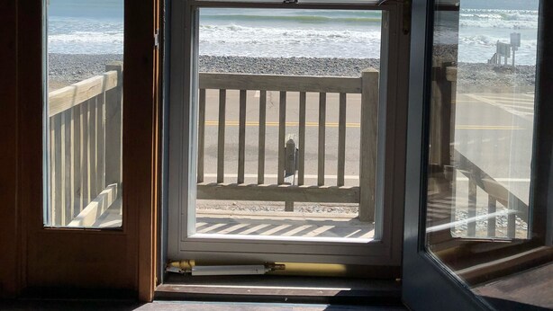 Vista desde una habitación con un ventanal grande con vista a la playa.
