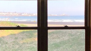 Una ventana con vista a la playa y un pueblo lejano.