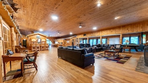 Een ruime lodge met houten vloeren, een grote bank en een eethoek.