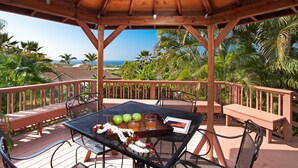 A wooden deck with a table, chairs, and a bench. - 5 ★ Nakukui Hale: Waterfall Pool, Gazebo & Ocean Views, Gated Kona Town Retreat (Kailua-Kona)