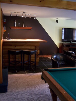 Relax in a spacious room with a pool table, bar area, and TV.