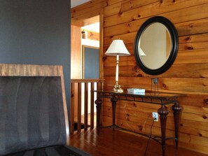 Cozy retreat with a sofa, round mirror, and wooden staircase.