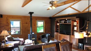 Interior acogedor de una cabaña con chimenea, asientos de cuero, una mesa de comedor y un televisor.