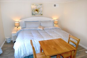 A neatly arranged bedroom with a bed, bedside lamps, a wooden table, and a chair.