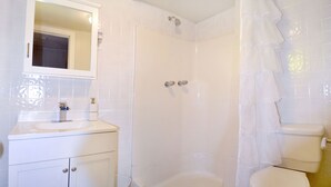 Un baño con lavamanos, espejo e inodoro blancos.
