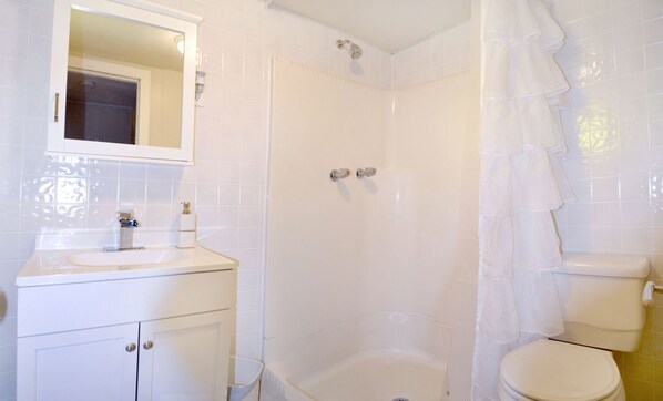 A bathroom with a white sink, mirror, and toilet.