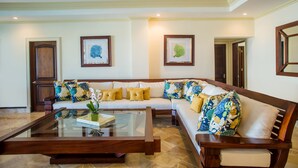 A spacious living room with a large wooden sofa, a glass coffee table, and two framed artworks on the wall. - Cap Cana Oceanfront Penthouse Marina Apartment, Sleeps 10, overlooks ocean (Punta Cana)