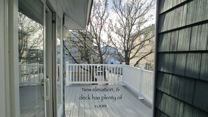 A wooden deck with a white railing, overlooking a residential area with trees and houses. - LAVALLETTE New Panoramic Deck, Outdoor shower, and Kitchen INCLUDES BEACH BADGES (Lavallette)