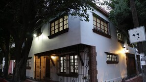 A two-story building with a white facade, multiple windows with black frames, and a gated entrance.