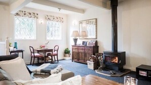 Una sala de estar acogedora con chimenea, un comedor con mesa y sillas, y una cocina con armarios y estufa.