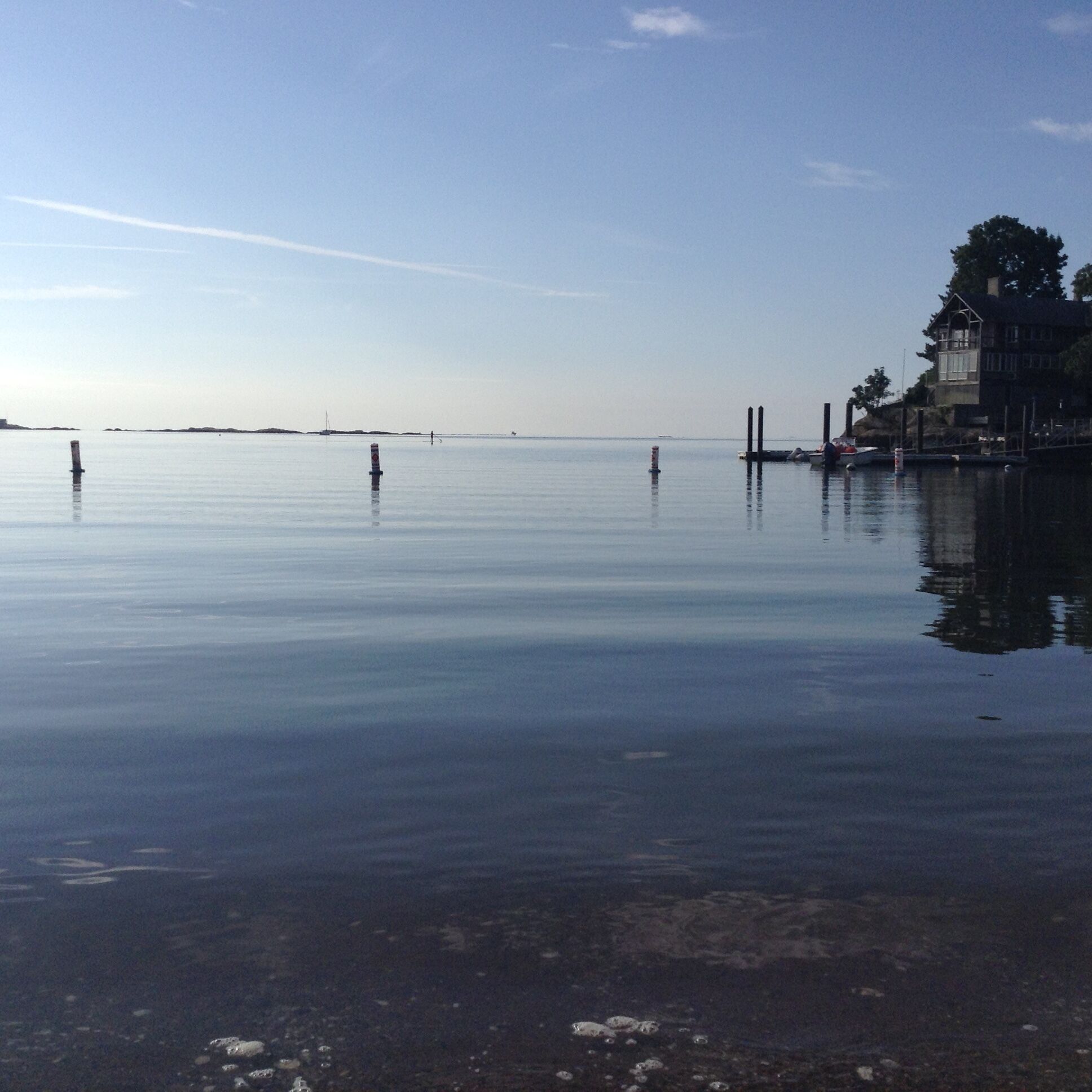 Un rivage paisible avec un quai, une eau calme et un bâtiment doté d’un balcon.