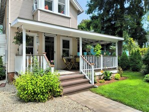 Une maison à deux étages dotée d’un porche abrité, d’une porte d’entrée et d’un petit espace extérieur aménagé avec une table et des chaises.