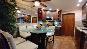 Una cocina moderna con armarios de madera, una mesa de comedor de vidrio y un ventilador de techo.