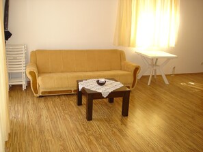 A living room with a sofa, a small table with a bowl, and a white table.