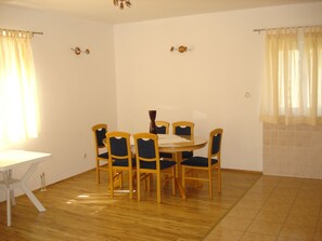 A dining area with a round table and six chairs, a white tablecloth, and a vase.