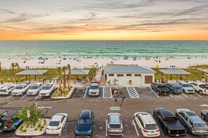 A parking lot with multiple cars and a beach in the background. - Blue Coconut | Private Pool | 6-Seater Golf Cart | Steps to Beach (Destin)
