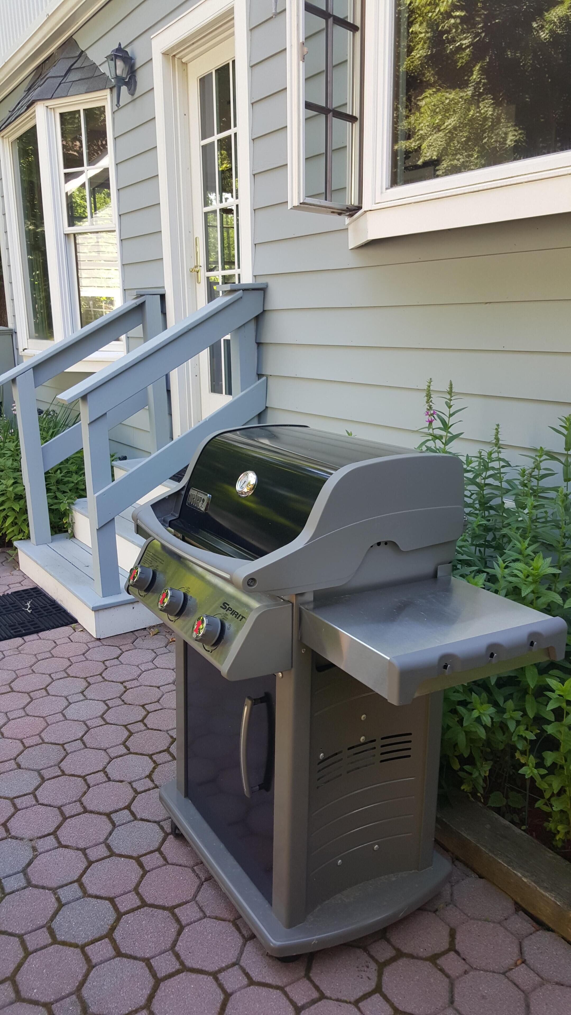 A portable gas grill with a digital display, placed on a paved patio.