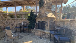 A stone fireplace with a mantel, surrounded by outdoor seating with chairs and tables. - The Resting Place on Pine Cove at Mountain Harbor (Mt Ida)