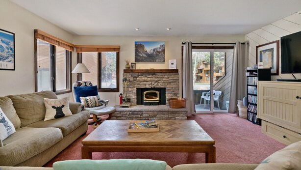 A cozy living room with a stone fireplace, a sofa, a coffee table, and a television.