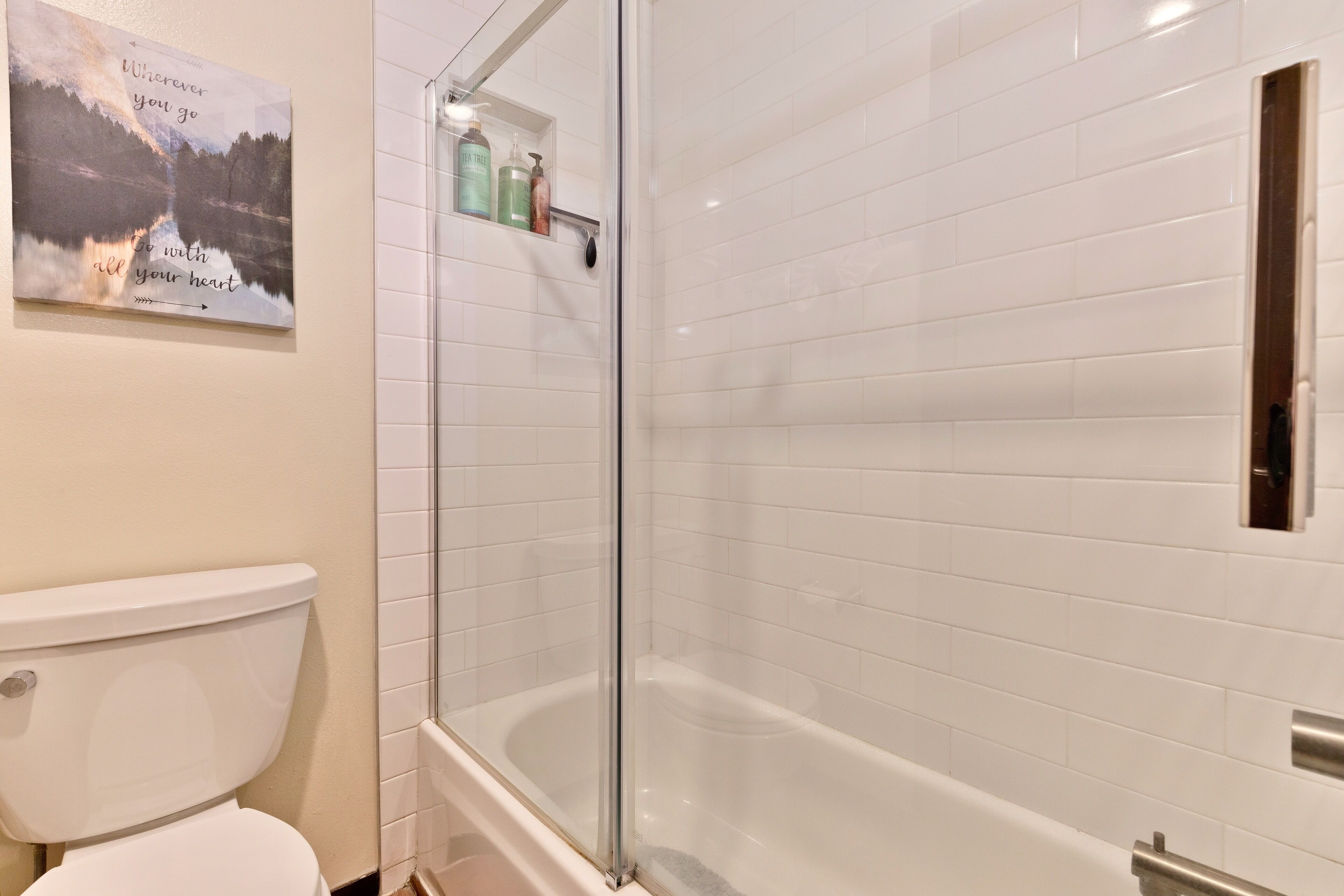 Een badkamer met toilet, een douche in een glazen cabine en een bad.